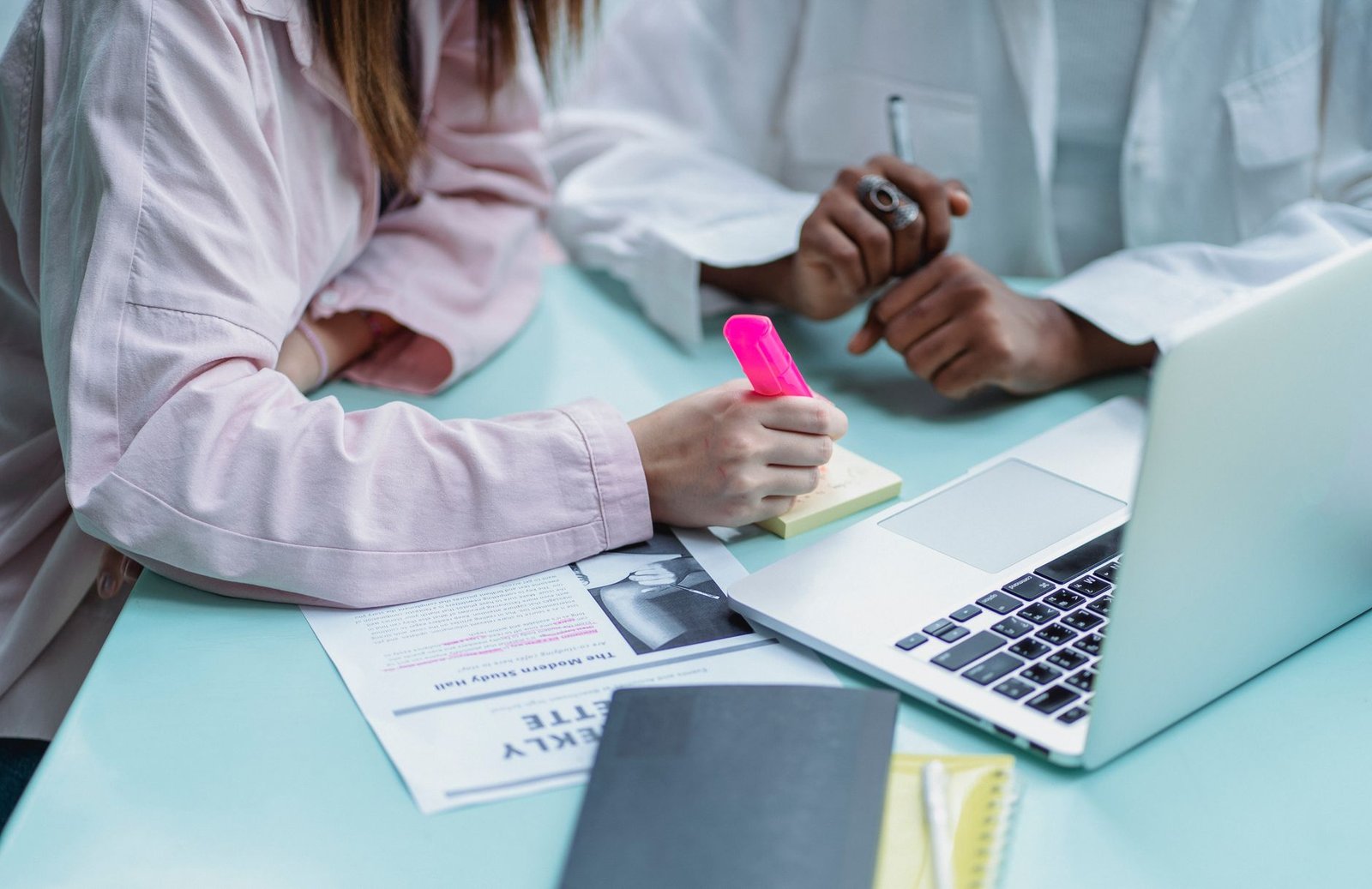 Hospital billing statements, a highlighter, and a laptop on a kitchen table while checking for itemized hospital bill errors