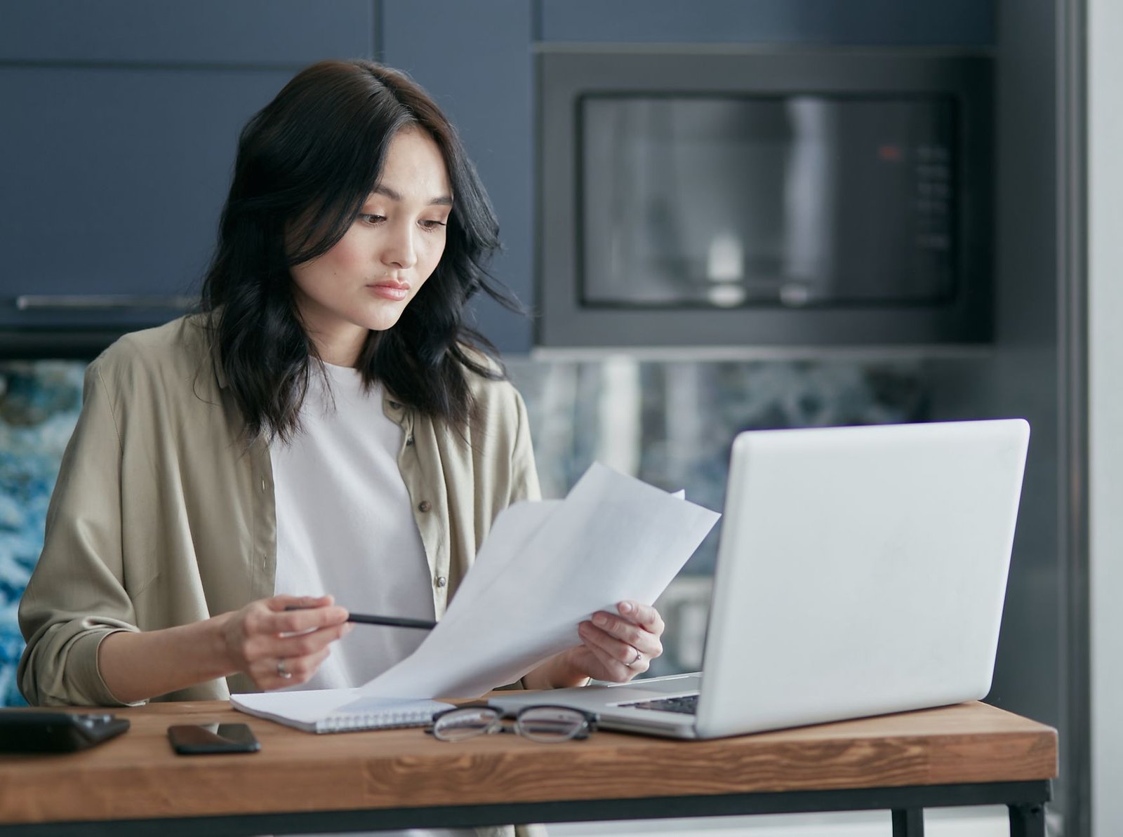 Person on the phone reviewing a health insurance claim denial letter at a kitchen table