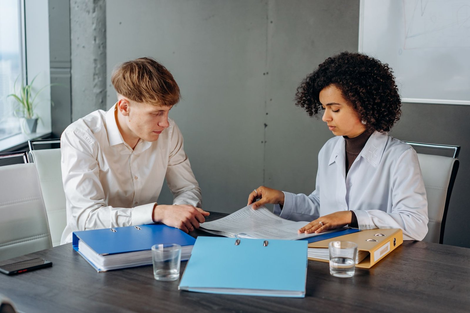 Two people assembling medical records and plan criteria for an independent review organization
